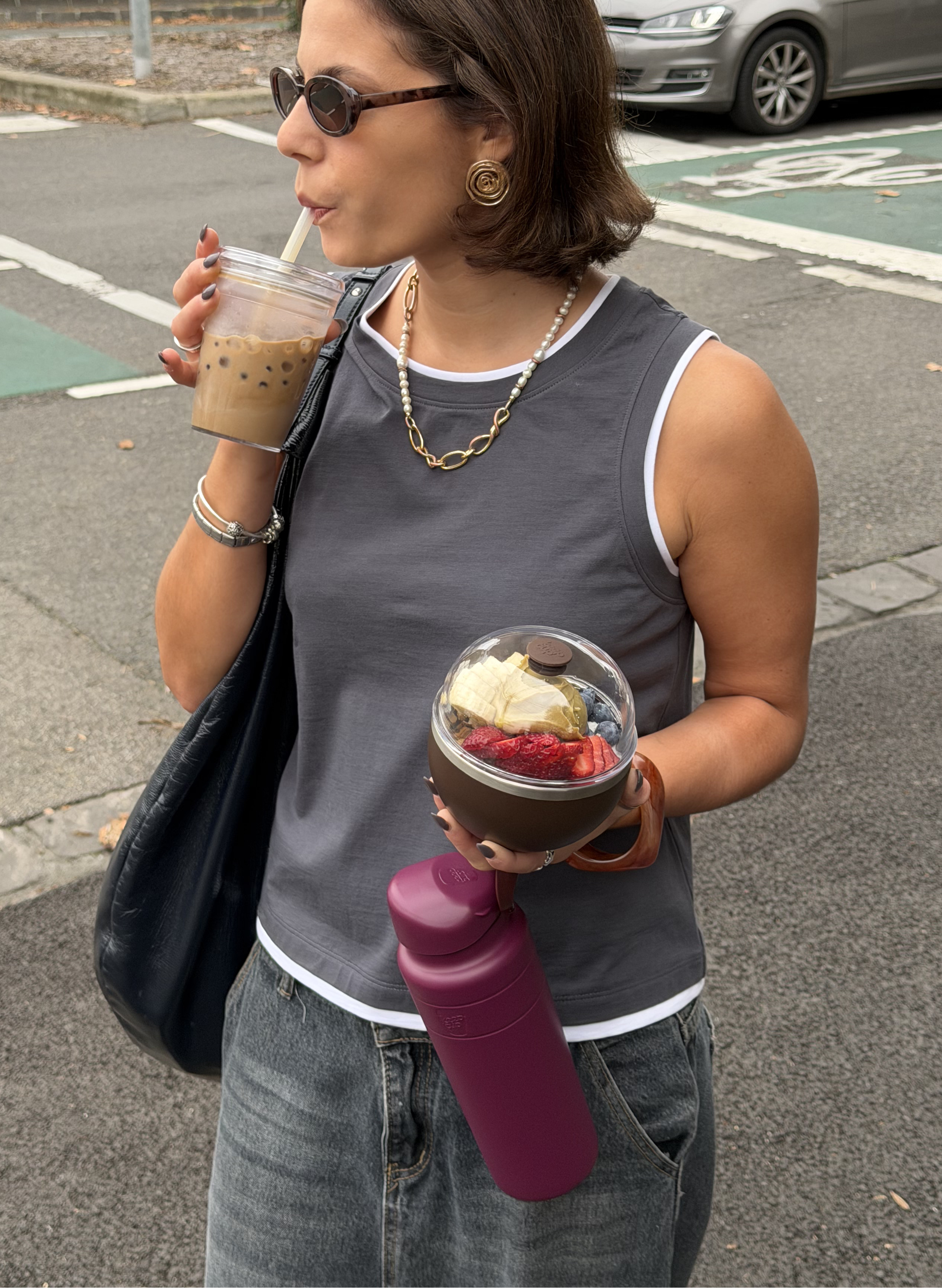Cool woman in sunglasses sipping boba from KeepCup Cold Cup with boba, carrying mulberry Ora Water Bottle and Go Bowl fuilled with acai.