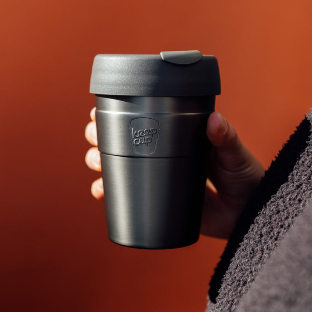 Person holding a nitro thermal KeepCup against an orange background