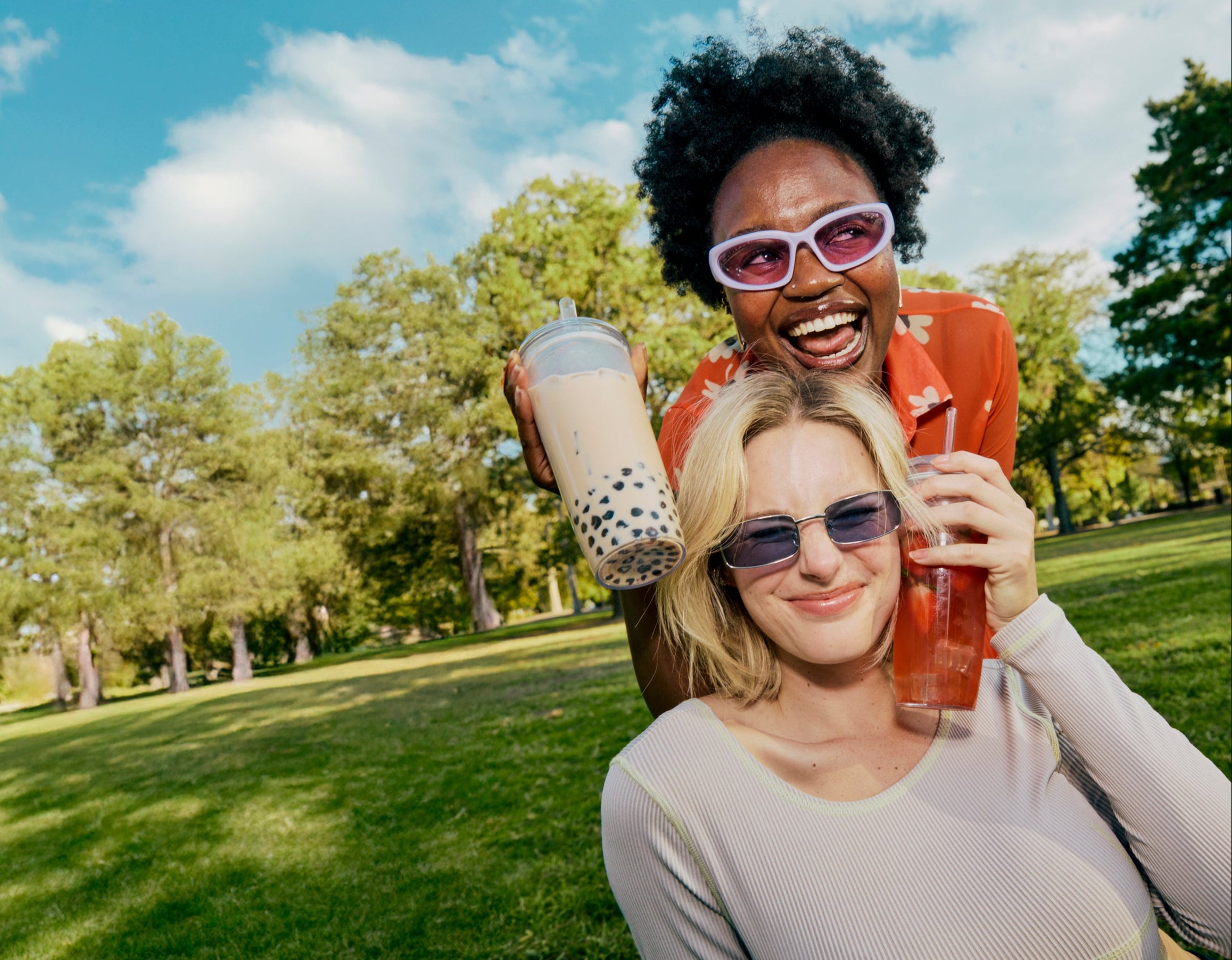 Two women enjoying drinks outdoors in a park