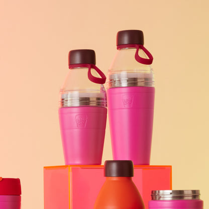 Two Pink KeepCup water bottles on an orange stand and peach background