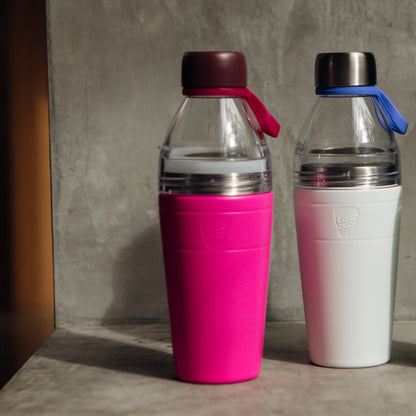 Two KeepCup water bottles (Pink and White) on a concrete surface.