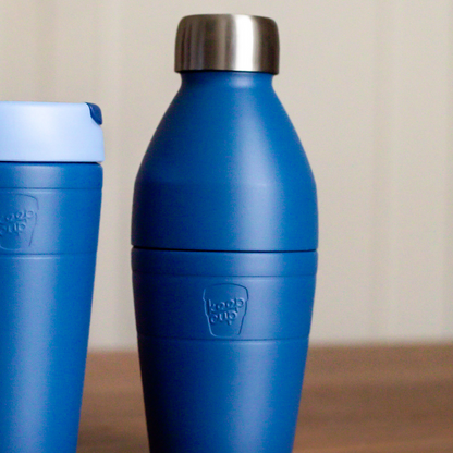 KeepCup blue insulated bottle with silver lid and Traveller cup in matching colourway on a wooden surface.