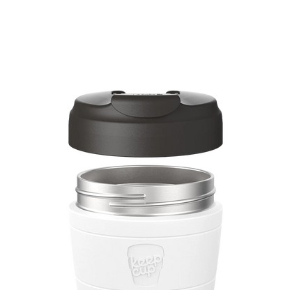 Black Commuter Flip Lid shown lifted above a white KeepCup with stainless steel rim, demonstrating how the lid separates from the cup body in an exploded product view.